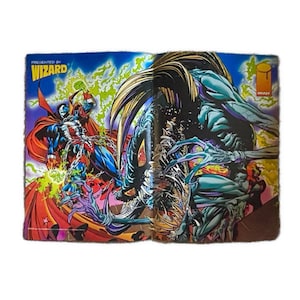 May include: A comic book cover featuring a red and black superhero character with a skull on his chest, fighting a blue and black creature with sharp claws. The cover is titled "Presented by Wizard".