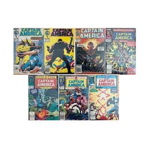 May include: A collection of seven Marvel Captain America comic books featuring colorful illustrated covers with various action scenes, character portraits, and bold text titles including Bloodstone, displayed in a grid layout against a white background.