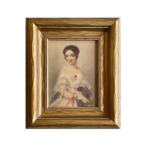 May include: A framed portrait of a woman in a white dress with a blue shawl. She is wearing a pearl necklace and a pink ribbon around her wrist. The frame is gold with a wood grain finish.
