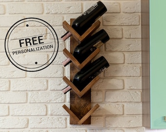 May include: A wooden wine rack with a chevron design, mounted on a white brick wall. The rack holds four bottles of wine. The rack is made of natural wood with a rustic finish. The rack is a great way to store and display your favorite wines.
