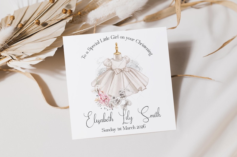 May include: A square card with a watercolor illustration of a baby dress on a dress form. The card reads "To a Special Little Girl on your Christening" and includes the name "Elizabeth Lily Smith" and the date "Sunday 1st March 2026".