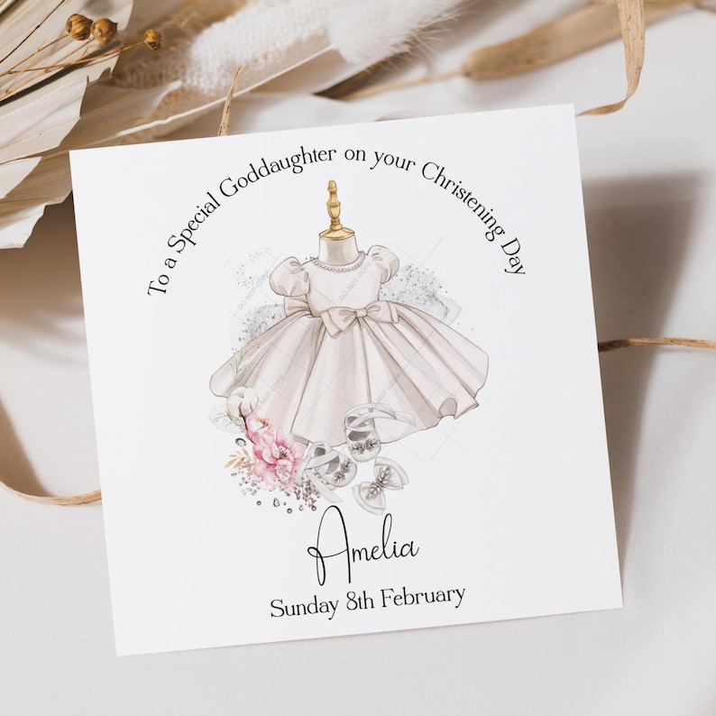 May include: A greeting card with a watercolor illustration of a white christening dress on a dress form. The card reads "To a Special Goddaughter on your Christening Day" and includes the name "Amelia" and the date "Sunday 8th February".