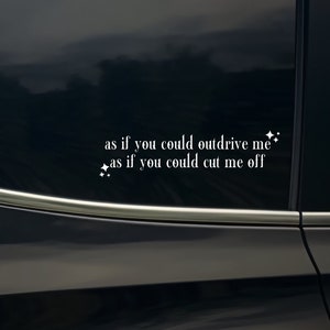 Op de afbeelding: Een zwarte auto met een witte vinyl sticker op de achterruit met de tekst "as if you could outdrive me * as if you could cut me off".