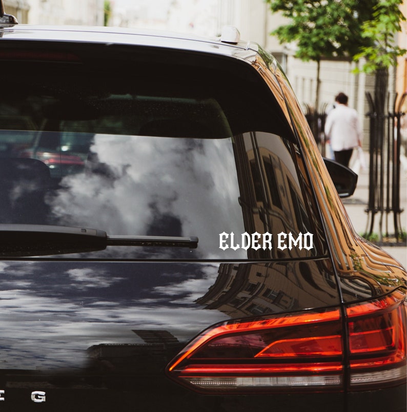 May include: Black car with a white vinyl sticker on the back window that says "ELDER EMO".