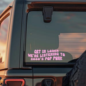 May include: A pink car sticker with the text "Get in loser we're listening to 2000's pop punk" in a bubble font.