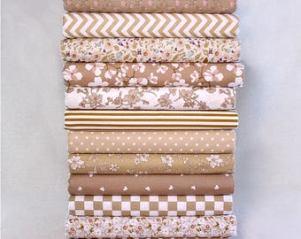 May include: A stack of various fabric rolls in shades of brown, beige, and white. Patterns include floral, chevron, polka dots, stripes, and checkered designs. The fabrics are neatly folded and stacked, showcasing a variety of textures and styles.