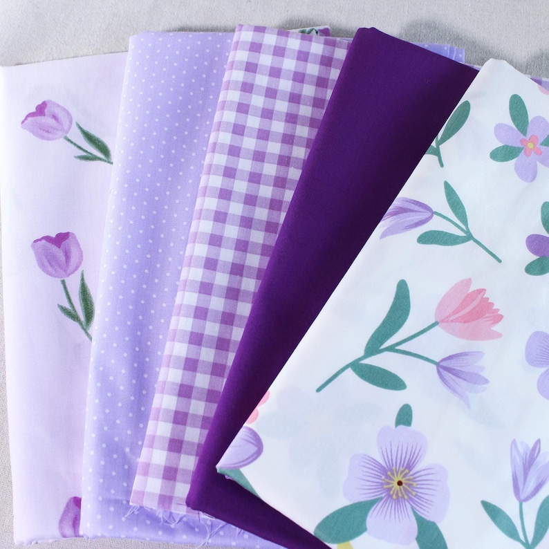 Puede incluir: Un mont&oacute;n de seis cuadrados de tela en varios tonos de morado y blanco. Las telas presentan diferentes patrones, incluyendo lunares, cuadros vichy e estampados florales.