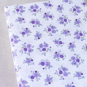 Puede incluir: Tela blanca con un patr&oacute;n repetido de peque&ntilde;as flores moradas y peque&ntilde;os puntos blancos.