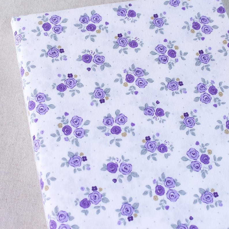 Puede incluir: Tela blanca con un patr&oacute;n repetido de peque&ntilde;as flores moradas y peque&ntilde;os puntos blancos.