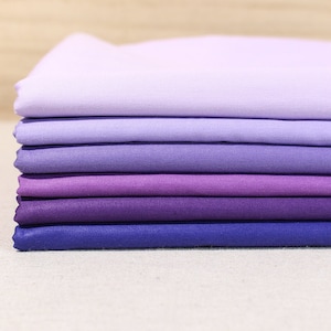 May include: A stack of six fabric swatches in shades of purple, ranging from light lavender to deep indigo.