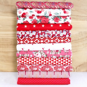 May include: A pile of folded fabric featuring a range of red and white patterns. Designs include floral, cherries, stars, geometric shapes, and polka dots. The fabrics are neatly stacked, displaying a variety of textures and prints.