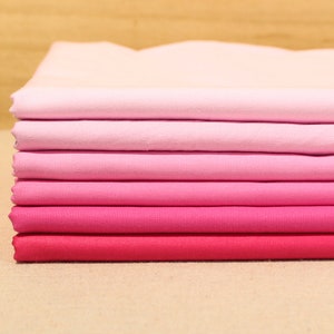 May include: A stack of pink and red fabric swatches, ranging from light pink to a deep red, showcasing a gradient of colors.