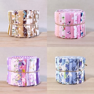 Peut inclure: Quatre rouleaux de tissu noués avec de la ficelle. Le rouleau en haut à gauche présente des motifs marron, beige et floraux. Le rouleau en haut à droite contient des imprimés roses, blancs et floraux. Le rouleau en bas à gauche a des motifs violets et floraux. Le rouleau en bas à droite montre des motifs bleus et floraux.