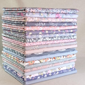 May include: A pile of folded fabric pieces in various floral and patterned designs. The fabrics feature a colour palette of pink, grey, and blue. The pile is neatly arranged, showcasing the different patterns and textures of the fabric.