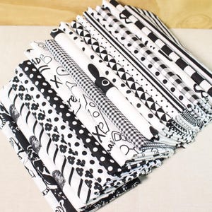 Op de afbeelding: Een stapel zwarte en witte stofvierkanten met verschillende patronen, waaronder stippen, strepen en geometrische patronen. De stof is perfect voor patchwork, naaien en knutselprojecten.
