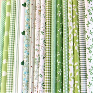 May include: A collection of 20 fabric strips in various shades of green and white with different patterns, including polka dots, stripes, gingham, and floral prints.