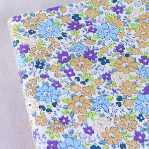 Puede incluir: Tela blanca con un patr&oacute;n floral con peque&ntilde;as flores azules, moradas y amarillas. La tela tiene un aspecto vintage.