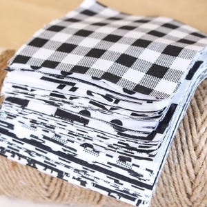 以下が含まれることがあります： 黒と白の異なるパターンを持つ布の正方形のスタック。一番上の正方形は黒と白の市松模様です。