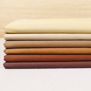 May include: A stack of eight fabric swatches in various shades of brown, from light beige to dark brown.