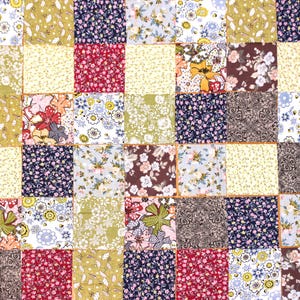 Pode incluir: Um edredom de patchwork composto por in&uacute;meros quadrados de tecido com diversos desenhos florais e estampados. Os quadrados apresentam cores como vermelho, azul, amarelo e verde, criando um t&ecirc;xtil vibrante e texturizado.