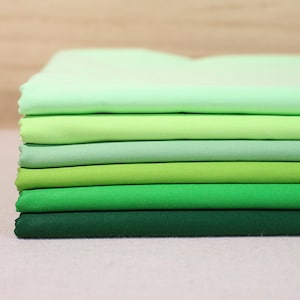 May include: A stack of eight fabric swatches in shades of green, ranging from light green to dark green.