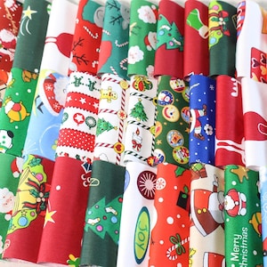 Peut inclure: Une collection de bandes de tissu pliées présentant divers motifs sur le thème de Noël, notamment le Père Noël, des sapins décorés, des sucres d'orge, des bonshommes en pain d'épices, des cloches et le texte Merry Christmas en rouge, vert, blanc et bleu.