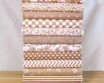 May include: A stack of rolled fabric bolts in various patterns and colors. The fabrics feature floral, polka dot, heart, and geometric designs in shades of tan, white, and brown. The fabrics are stacked on a wooden surface.