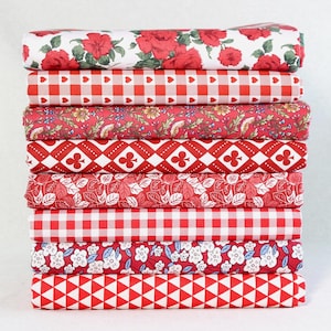 Może przedstawiać: Stos różnych tkanin w czerwono-białe wzory. Wzory obejmują róże, kratę vichy z sercami, kwiaty, romby z symbolami koniczyny, wzory liści i trójkąty. Tkaniny są starannie złożone i ułożone w stos.