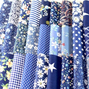 May include: A collection of folded fabric swatches in various shades of blue. The fabrics feature diverse patterns, including floral, polka dots, stripes, and geometric designs. The swatches are arranged in a neat, organized display, showcasing the variety of textures and prints.