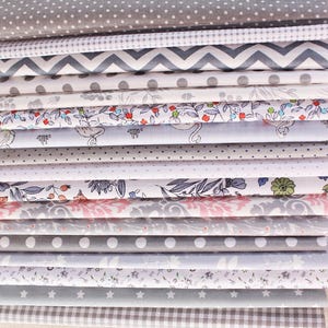 Puede incluir: Una pila de muestras de tela variadas en tonos grises, blancos y rosas. Los patrones incluyen lunares, chevrones, florales y estrellas. Las telas están cuidadosamente dobladas, mostrando una variedad de texturas y diseños adecuados para proyectos de costura y manualidades.