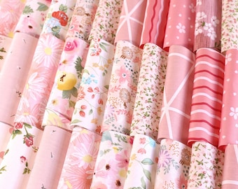 May include: A collection of pink and white fabric scraps with floral and geometric patterns. The fabrics are arranged in a fan shape, with the pink fabrics on the bottom and the white fabrics on the top.
