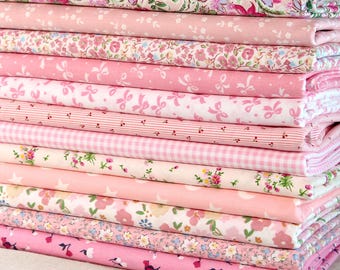 May include: A pile of pink fabric featuring diverse floral and patterned designs. The fabrics include floral prints, bows, stripes, and gingham checks in shades of pink and white. The fabrics are neatly folded and stacked, showcasing a variety of textures and patterns.