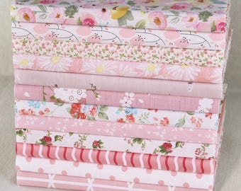 May include: A pile of assorted pink patterned fabrics. The fabrics display floral designs, including roses and daisies, alongside stripes, polka dots, and geometric shapes. The colour scheme is predominantly pink, with touches of white, red, and yellow.