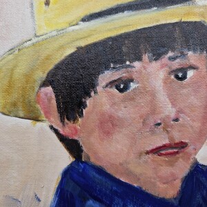 May include: Oil painting portrait of a young person wearing a yellow hat and a blue shirt. The subject has dark hair, fair skin, and a slightly somber expression. The artwork is painted on canvas.