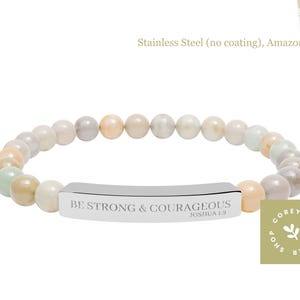 May include: A beaded bracelet with a stainless steel bar. The bracelet features a mix of neutral-toned beads and a silver bar engraved with "BE STRONG & COURAGEOUS" and "JOSHUA 1:9". The bracelet is made of Amazonite.