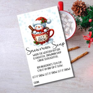 Peut inclure: Une étiquette cadeau imprimable représentant un bonhomme de neige dans une tasse rouge avec le texte "Let it Snow". L'étiquette indique "Snowman Soup" et comprend des instructions pour faire la soupe.
