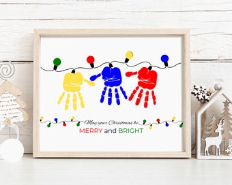 Puede incluir: Una tarjeta de Navidad con un diseño de huellas de manos. Tres huellas de manos de colores están enhebradas con una cadena de luces. El texto dice "May your Christmas be Merry and Bright".