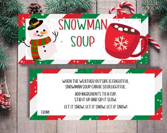 May include: A printable snowman soup gift tag with red and green stripes. The tag features a snowman with a red and green scarf and a red mug with marshmallows and a snowflake. The text on the tag reads "SNOWMAN SOUP" and "WHEN THE WEATHER OUTSIDE IS FRIGHTFUL. SNOWMAN SOUP CAN BE SO DELIGHTFUL. ADD INGREDIENTS TO A CUP. STIR IT UP AND SIP IT SLOW. LET IT SNOW. LET IT SNOW. LET IT SNOW!"