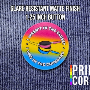 May include: A round button with a matte finish, featuring a design in the colors of the pansexual pride flag. The button has the text "I WASN'T IN THE CLOSET, I WAS IN THE CUPBOARD" and measures 1.25 inches in diameter.