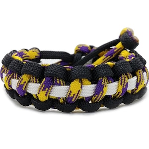 May include: A black, white, and purple braided bracelet with a white stripe.