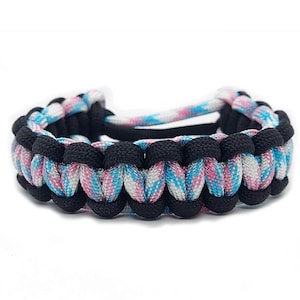 May include: A black and blue and pink paracord bracelet with a woven design.