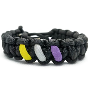 May include: Black paracord bracelet with yellow, white, and purple stripes. The bracelet is woven in a knot pattern.