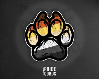 May include: A sticker featuring a paw print design with the colors of the Bear Pride flag. The paw print has a black outline and a white border. The text "PRIDE CORDS" is at the bottom in a rainbow color scheme.