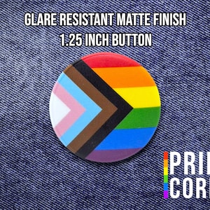 May include: A round, 1.25-inch button with a matte finish, featuring a colorful design representing the LGBTQ+ community. The button has a rainbow and transgender flag design. The text "GLARE RESISTANT MATTE FINISH 1.25 INCH BUTTON" is at the top. The words "PRIDE CORDS" are at the bottom.