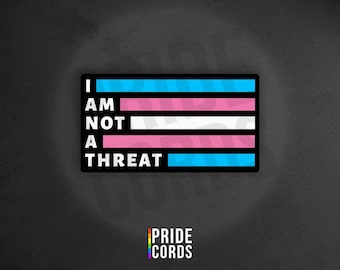 May include: Rectangular sticker with the text "I AM NOT A THREAT" in white, arranged over horizontal stripes of light blue, pink, white, and light blue. The Pride Cords logo is at the bottom.
