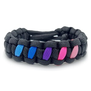 May include: A black paracord bracelet with a woven design featuring blue, purple, and pink stripes.