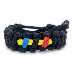 May include: Black paracord bracelet with yellow, blue, and red woven stripes.