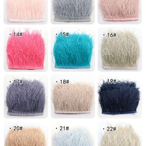 Puede incluir: Doce muestras de ribete de plumas en varios colores, incluyendo rosa, gris, turquesa, azul y beige. Cada muestra est&aacute; etiquetada con un n&uacute;mero del 11 al 22.
