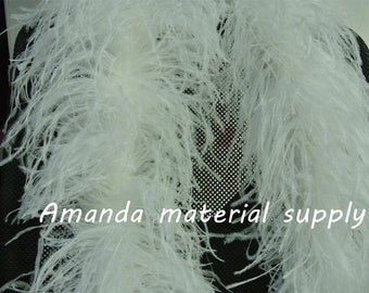 May include: Two white ostrich feather boas, arranged on a black chair. The boas are long and fluffy, with a soft, delicate texture. The text "Amanda material supply" is visible at the bottom of the image.