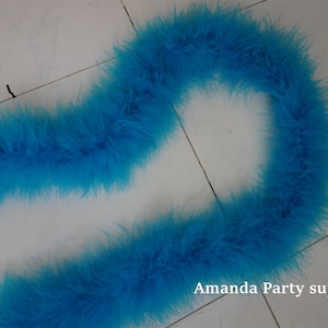 Op de afbeelding: Een lange, felblauwe verenboa. De boa is gemaakt van zachte, pluche veren en is perfect om elke outfit een vleugje glamour te geven.